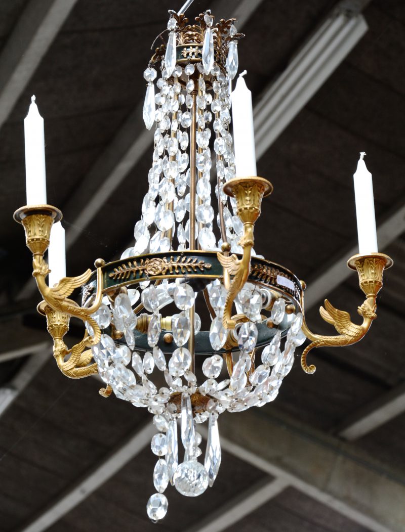 Een Empire-stijl halluchter met vijf kaarspunten en 5 lampen binnenin en kristallen pendeloques.