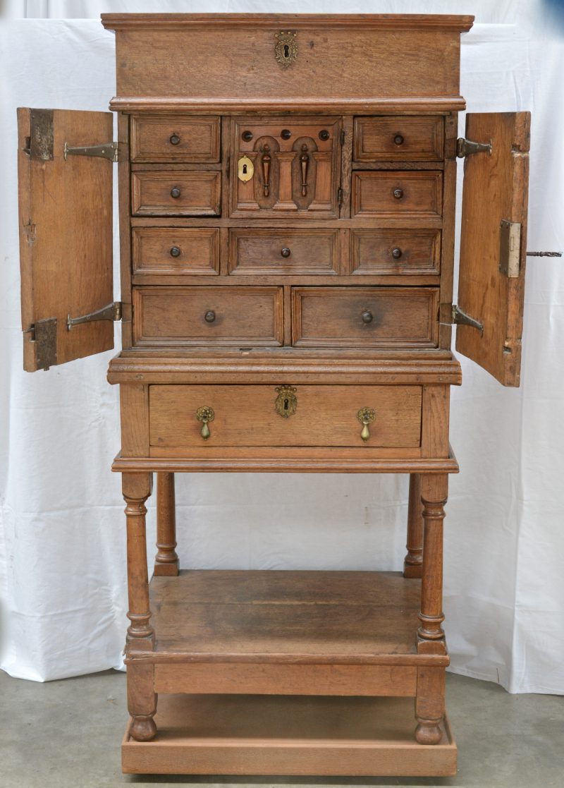 Een eikenhouten Mechels kabinet met bovenaan een klapblad en onderaan een lade. Achter de paneeldeurtjes acht kleine schuifjes en een secreet. XIXe eeuw.