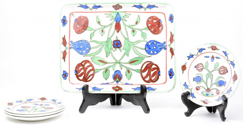 Een dienbladje en vier onderzetters van aardewerk, versierd met meerkleurige bloemendecors.
