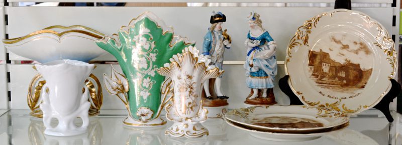 Een lot porselein, bestaande uit drie borden met zichten op Hoei, een koppel in XVIIIe eeuwse klederdracht, en vier verschillende hoornvazen.