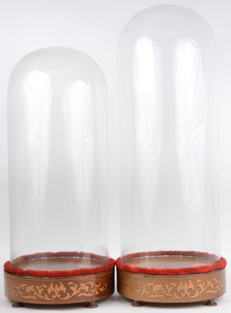 Twee glazen stolpen op met marquetterie versierde voet.