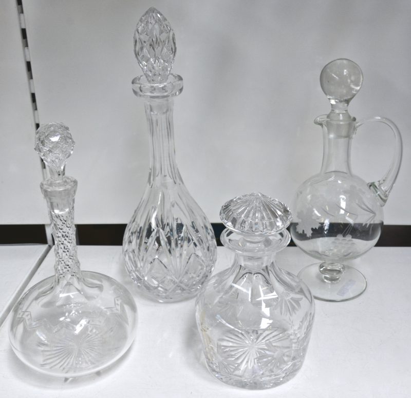 Vier diverse karaffen van kleurloos kristal en glas.