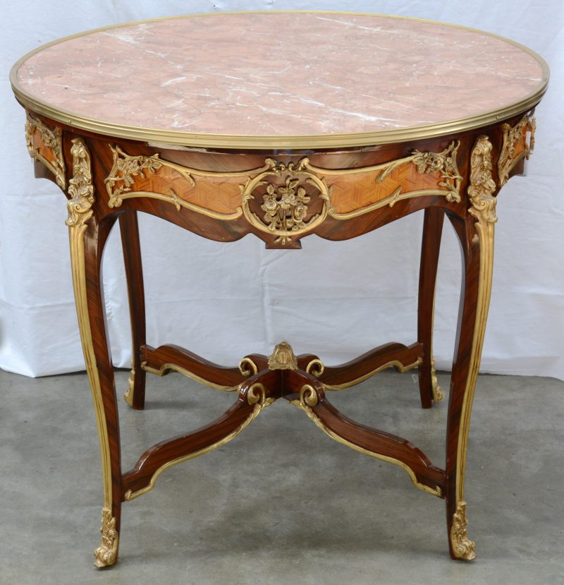 Een ronde tafel met roze marmeren blad in Louis XV stijl.