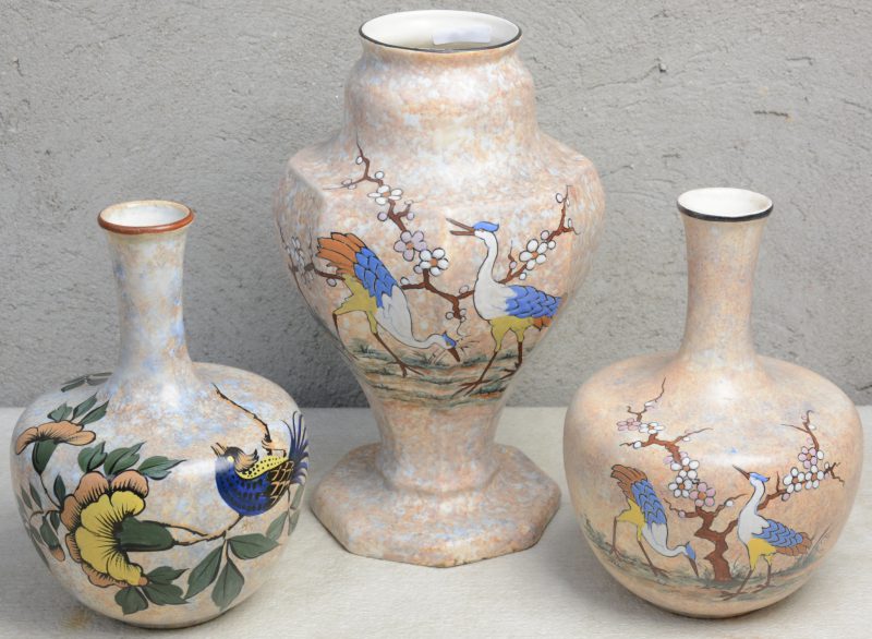 Drie aardewerken vazen met meerkleurige decors van A. Dubois, waarbij twee met reigers en bloesems en één met een vogel op een tak. Gesigneerd.