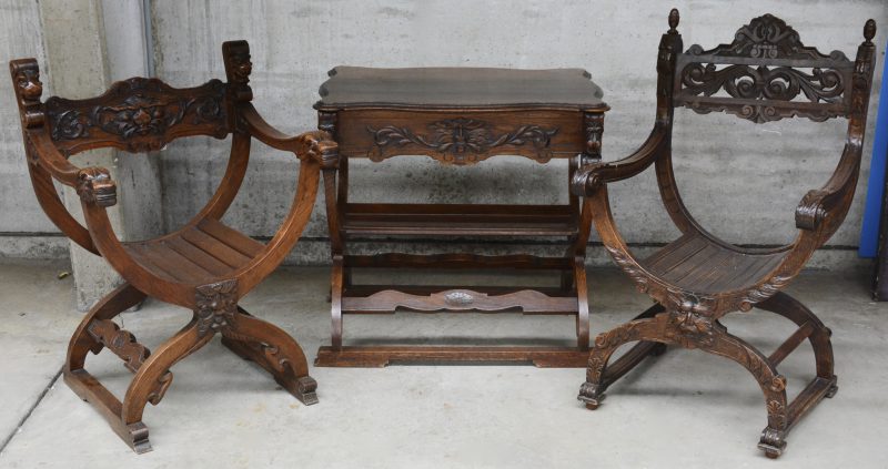 Een ensemble, bestaande uit twee verschillende dagobertstoelen en een gelijkaardig tafeltje van gebeeldhouwd eikenhout.