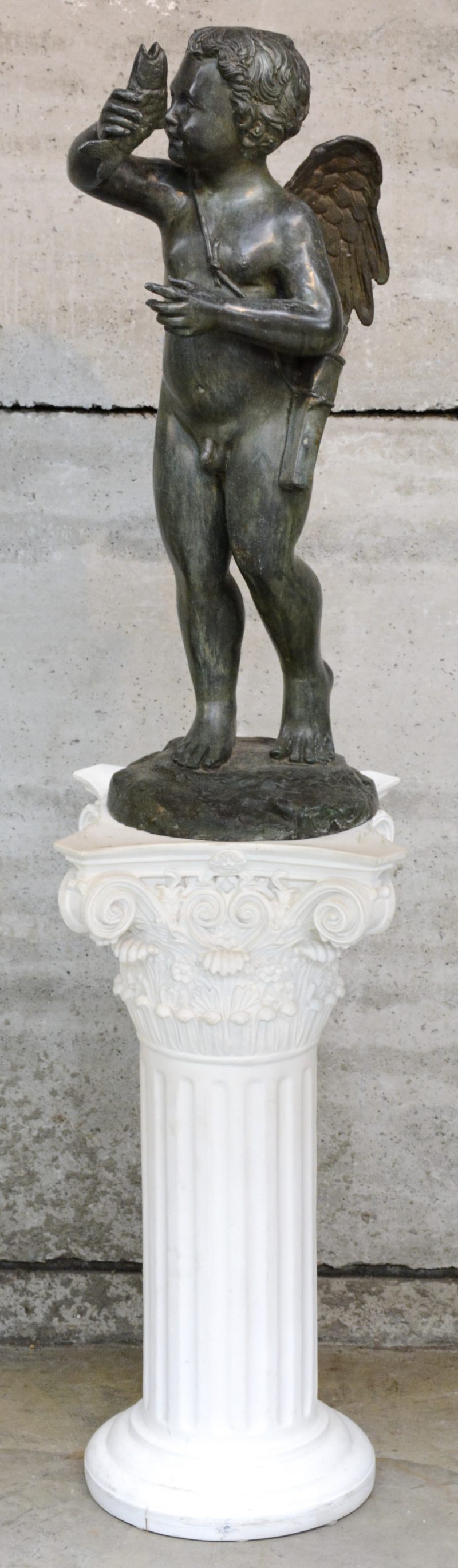 “Engel met vis”. Een bronzen beeld als fontein. Bijgevoegd een pîëdestal van kunststof in de vorm van een Corinthische zuil.