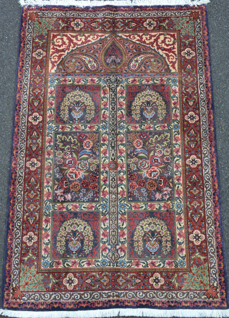Een handgeknoopt Perzisch wollen karpet met bloemenvazen in het decor.