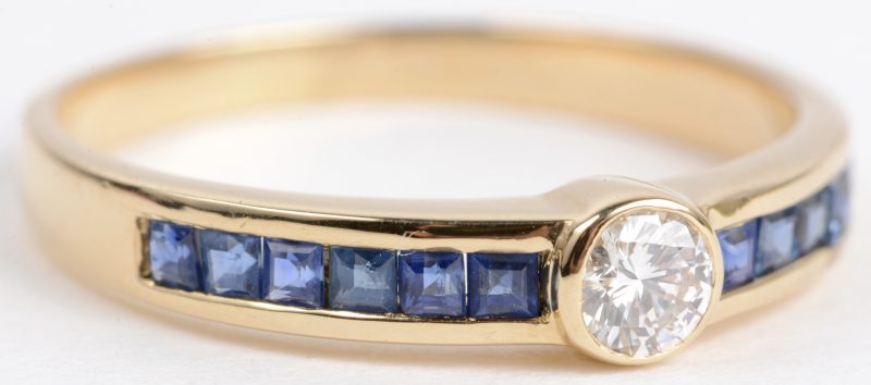 Een 18 karaats geel gouden ring bezet met één diamant van ± 0,15 ct. en saffier baguetten een gezamenlijk gewicht van ± 1 ct.