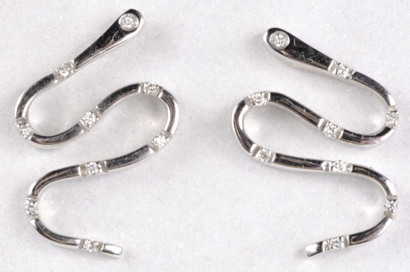 Een paar 18 karaats wit gouden oorbellen bezet met diamanten met een gezamenlijk gewicht van ± 0,14 ct.