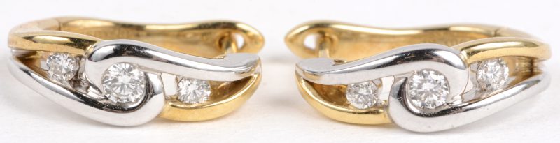 Een paar 18 karaats wit en geel gouden oorbellen bezet met diamanten met een gezamenlijk gewicht van ± 0,20 ct.