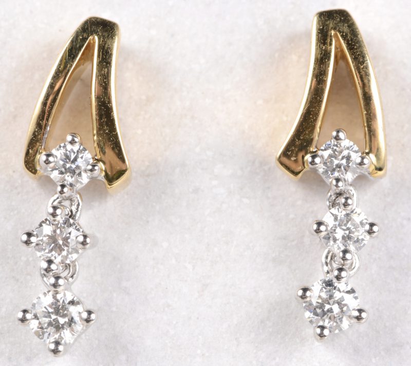 Een paar 18 karaats wit en geel gouden oorbellen bezet diamanten met een gezamenlijk gewicht van ± 0,25 ct.