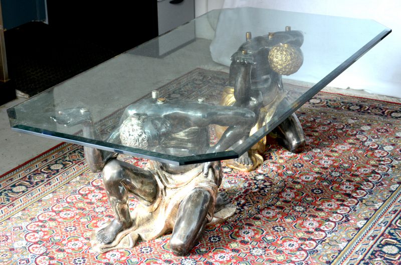Een glazen salontafel, gedragen door twee Morianen van kunststof.