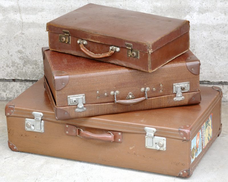 Een set van drie oude reiskoffers in oplopende formaten.