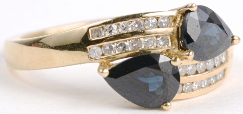 Een 18 karaats geel gouden ring bezet met een diamanten met een gezamenlijk gewicht van ± 0,24 ct. en twee saffieren met een gezamenlijk gewicht van ± 1 ct.