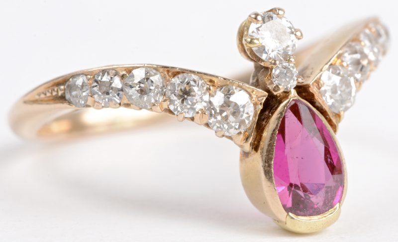 Een 18 karaats geel gouden ring bezet met diamanten met een gezamenlijk gewicht van ± 0,60 ct. en een peervormige robijn van ± 0,50 ct.