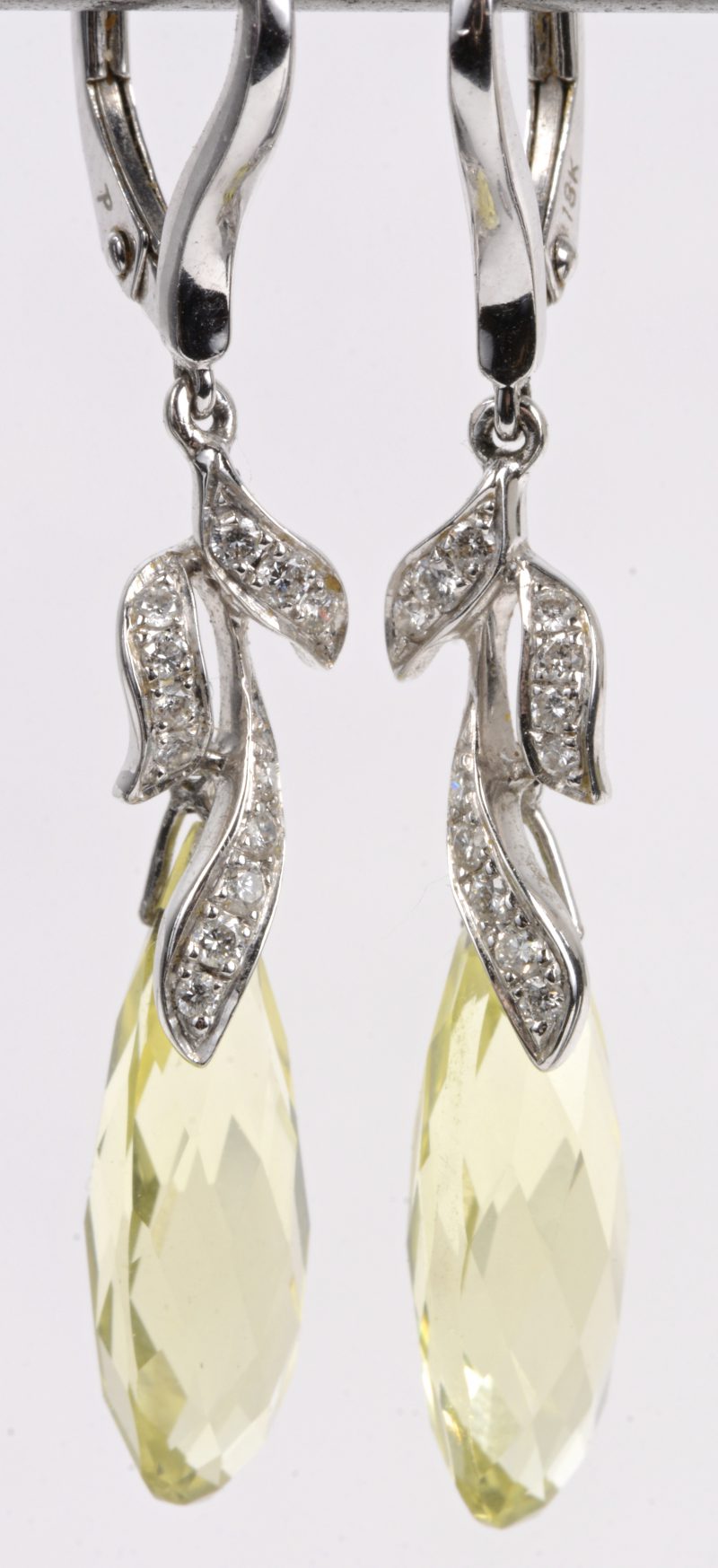 Een paar 18 karaats wit gouden oorbellen bezet met diamanten met een gezamenlijk gewicht van ± 0,20 ct. en twee in briolette geslepen peridots.