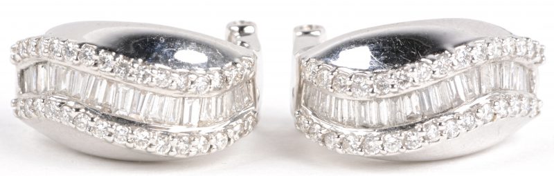 Een paar 18 karaats wit gouden oorbellen bezet met diamanten en diamant baguetten met een gezamenlijk gewicht van ± 1,50 ct.