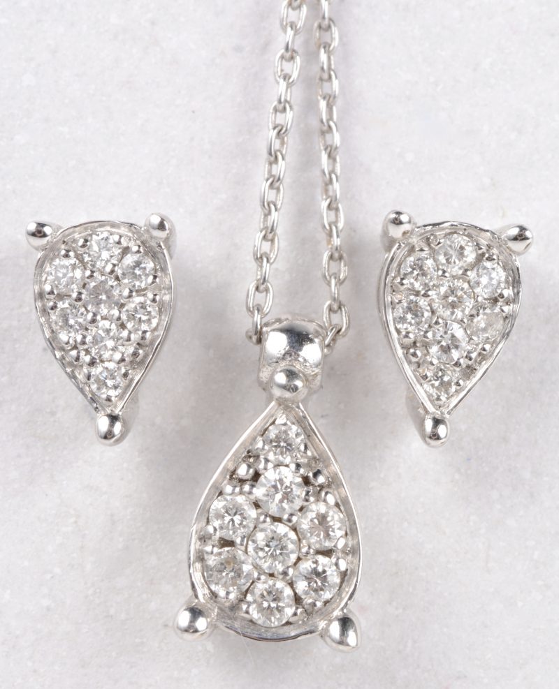 Een 18 karaats wit gouden ketting met hanger en bijpassende oorbellen bezet met diamanten met een gezamenlijk gewicht van ± 0,32 ct.