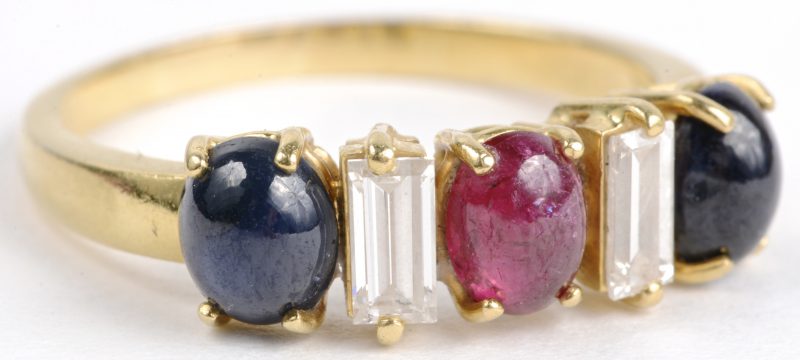 Een 18 karaats geel gouden ring bezet met diamant baguetten met een gezamenlijk gewicht van ± 0,40 ct. en robijn en saffier cabochon met een gezamenlijk gewicht van ± 0,75 ct.