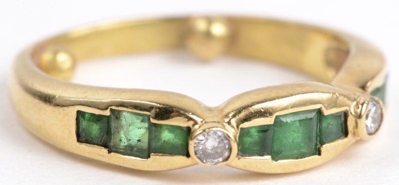Een 18 karaats geel gouden ring bezet met twee diamanten met een gezamenlijk gewicht van ± 0,10 ct. en smaragd baguetten met een gezamenlijk gewicht van ± 0,60 ct.