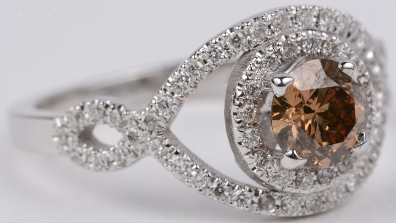 Een 18 karaats wit gouden ring bezet met een centrale cognac kleurige diamant van ± 0,50 ct. en briljanten met een gezamenlijk gewicht van ± 0,60 ct.