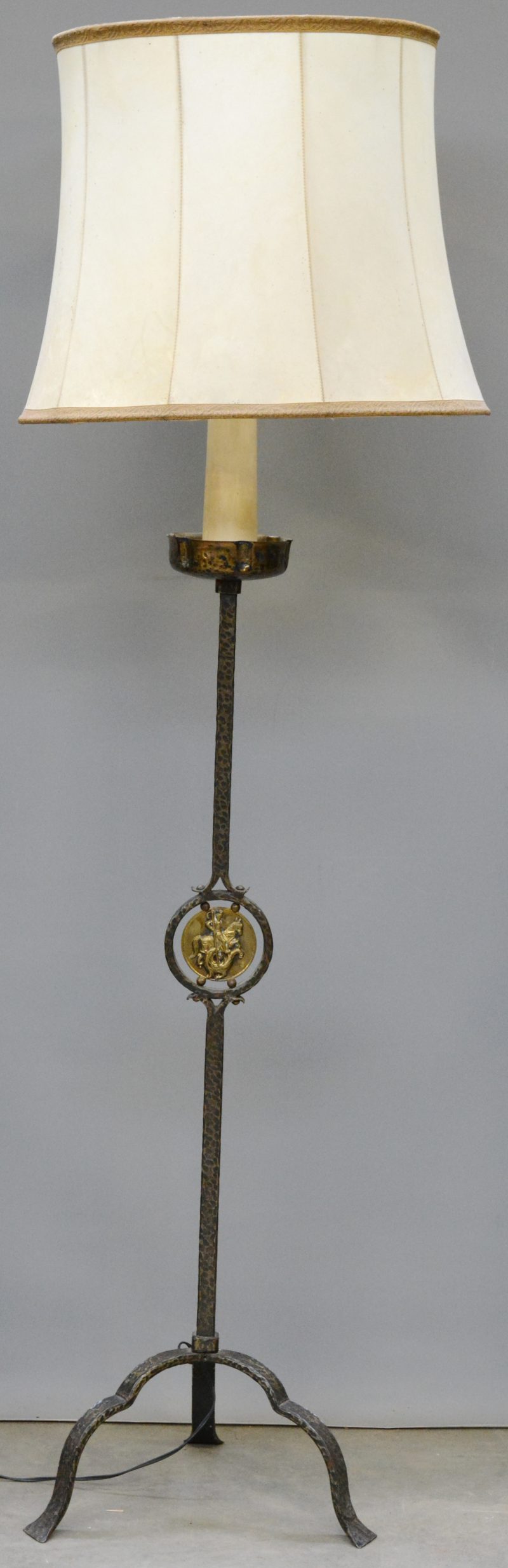 Een smeedijzeren staande lamp met een messingen plaquette van Sint Joris.
