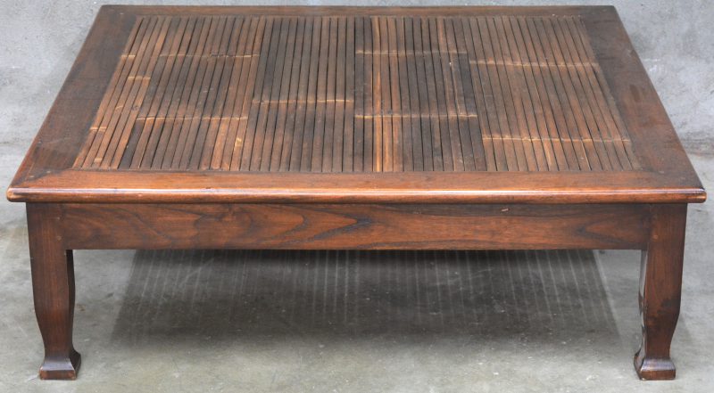 Een vierkante salontafel met een blad van bamboe.