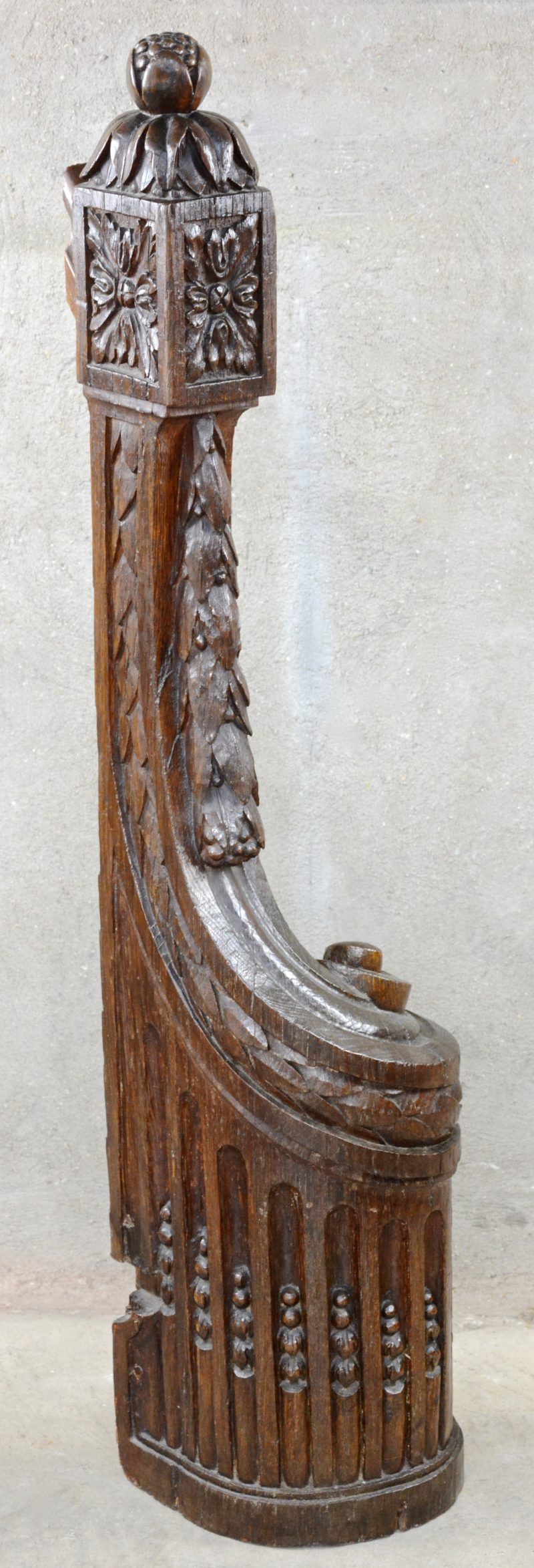 Een uiteinde van een trapleuning van gebeeldhouwd eikenhout in Lodewijk XVI-stijl.