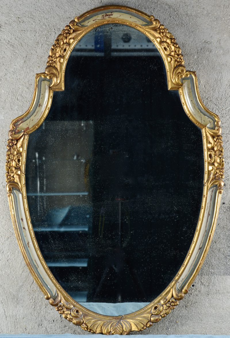 Een spiegel in goudgepatineerde houten lijst.