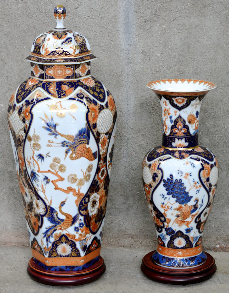 Twee vazen van porselein met een Imari decor. Met houten sokkels.