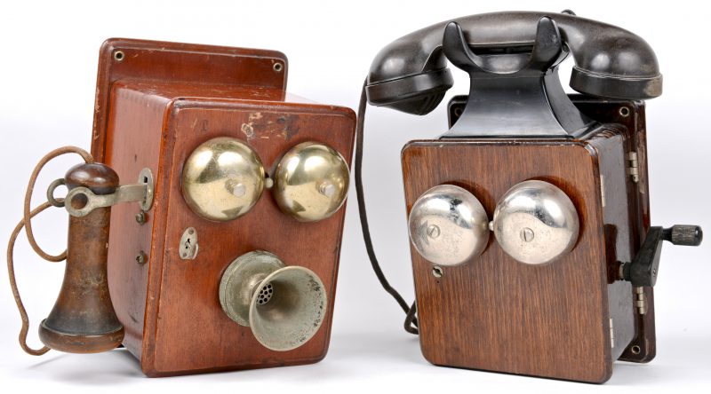 Twee oude houten wandtelefoons met bakelieten hoorn. Een gedateerd 1947 binnenin. Eén sleuteltje manco.