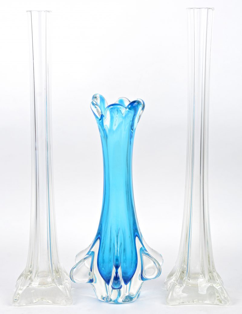 Een vaasje van blauw Muranoglas en twee langerekte kleurloze vazen.