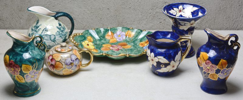 Een lot Bergens aardewerk met glansglazuur, bestaande uit een theepot, vier kannen, een vaas een een schotel, versierd met verschillende meerkleurige decors. Onderaan gemerkt.