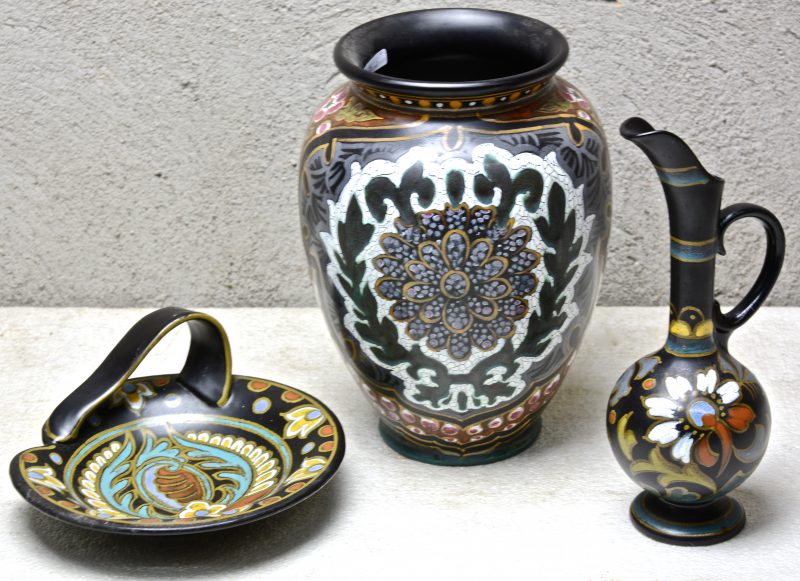 Drie stuks Gouds plateel, bestaande uit een grote vaas met decor ‘Congola’, een kruikje met decor ‘Bernadet’ en een schaaltje met decor ‘Effect’. Onderaan gemerkt.