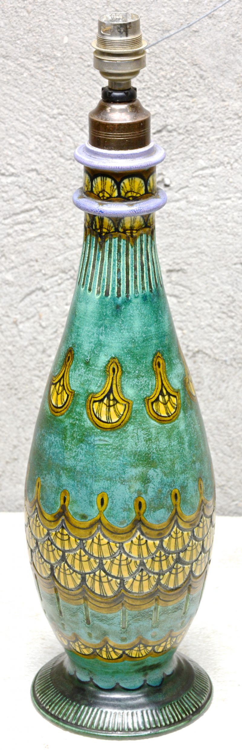 Een lampvoet van meerkleurig Gouds plateel, versierd met een meerkleurig reliëfdecor. Onderaan gemerkt.