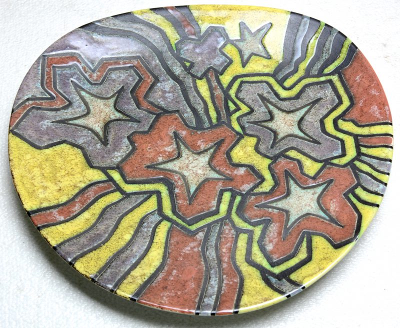 Een sierbord van meerkleurig aardewerk met reliëfdecor ‘Inca’. Onderaan gemerkt.