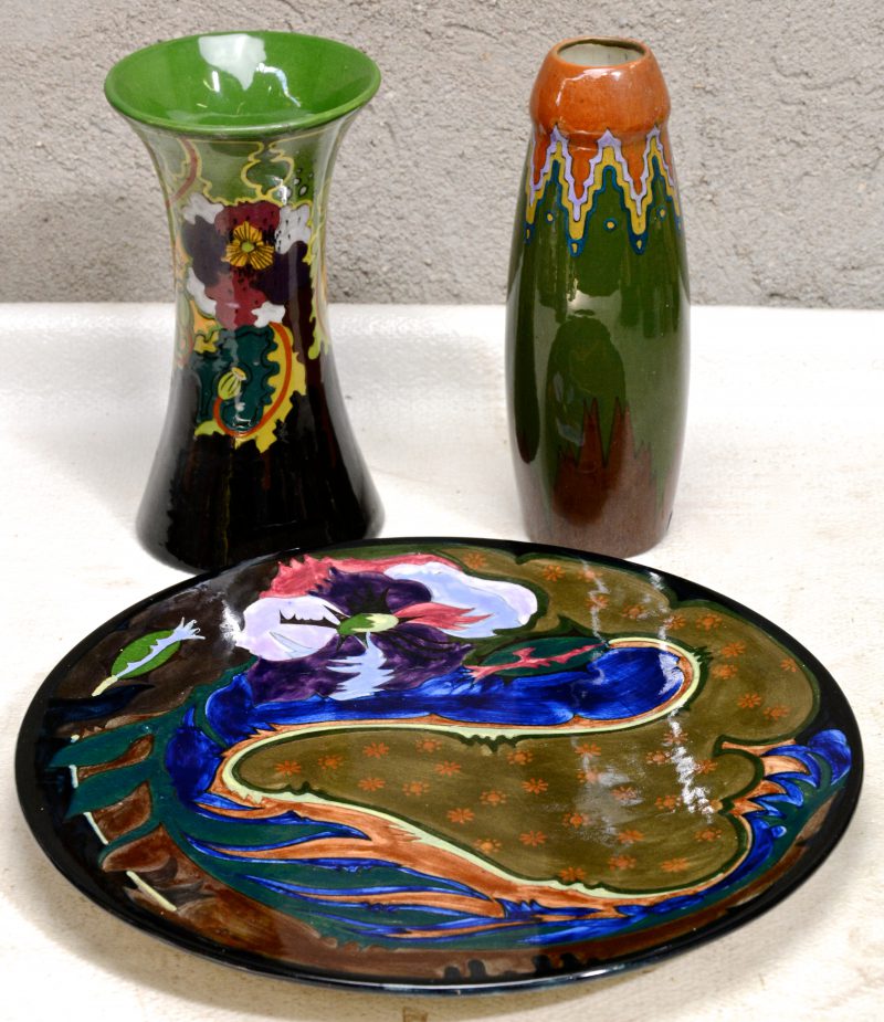 Drie stuks Gouds plateel, bestaand uit een ronde schotel en een vaas van Plazuid en een vaas van Ivora. Onderaan gemerkt.