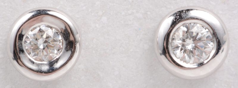 Een paar 18 karaats wit gouden oorbellen bezet met diamanten met een gezamenlijk gewicht van ± 0,14 ct.