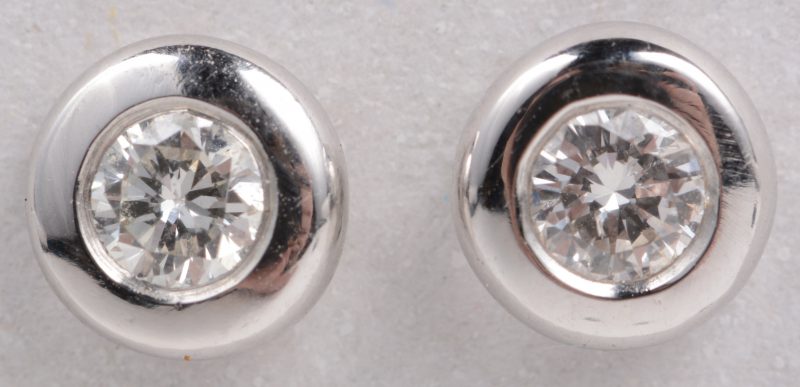 Een paar 18 karaats wit gouden oorbellen bezet met diamanten met een gezamenlijk gewicht van ± 0,24 ct.