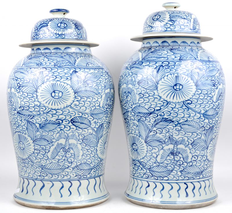 Een paar dekselvazen van Chinees porselein met blauw op witte florale decors.