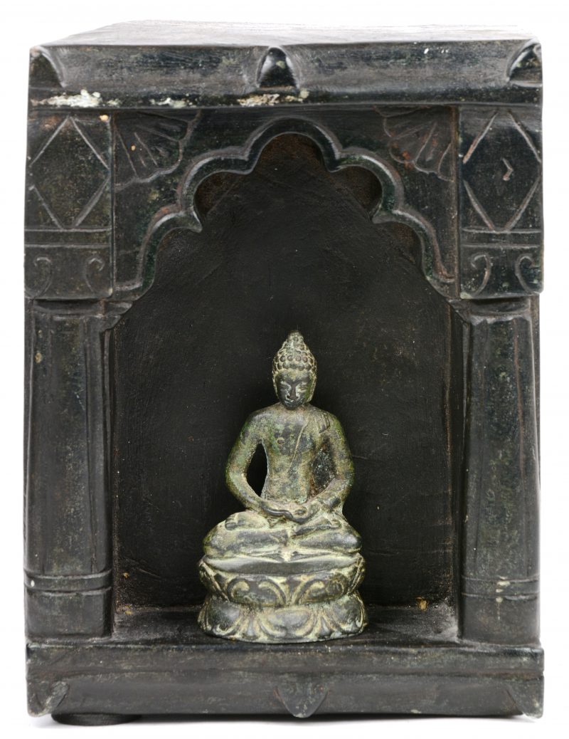 Een gesculpteerd stenen altaartje met een bronzen Boeddhabeeldje.