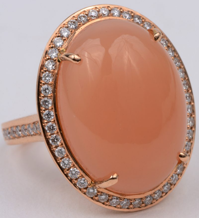Een 18 karaats rooskleurige gouden ring bezet met diamanten met een gezamenlijk gewicht van ± 0,62 ct. en een oranje maansteen van ± 14,58 ct.