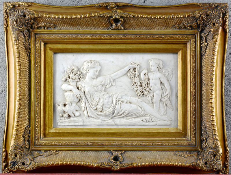 Een wit marmeren bas-reliëf met een voorstelling van Venus en Cupido. Achteraan met stempel “Arts and commerce promoted”.
