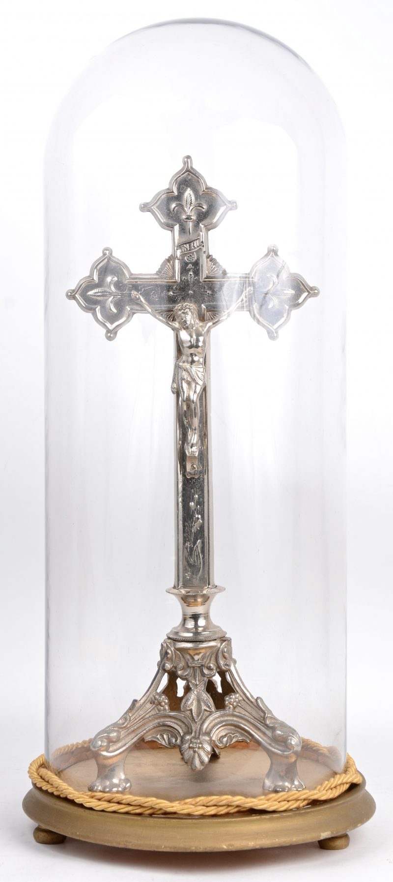 Een verzilverd kruisbeeld onder glazen stolp.