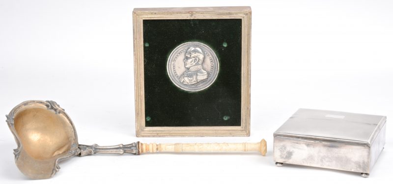 Een zilveren sauslepel met benen handvat, een verzilverde sigarettendoos en een Belgische zilveren munt uit 1849.