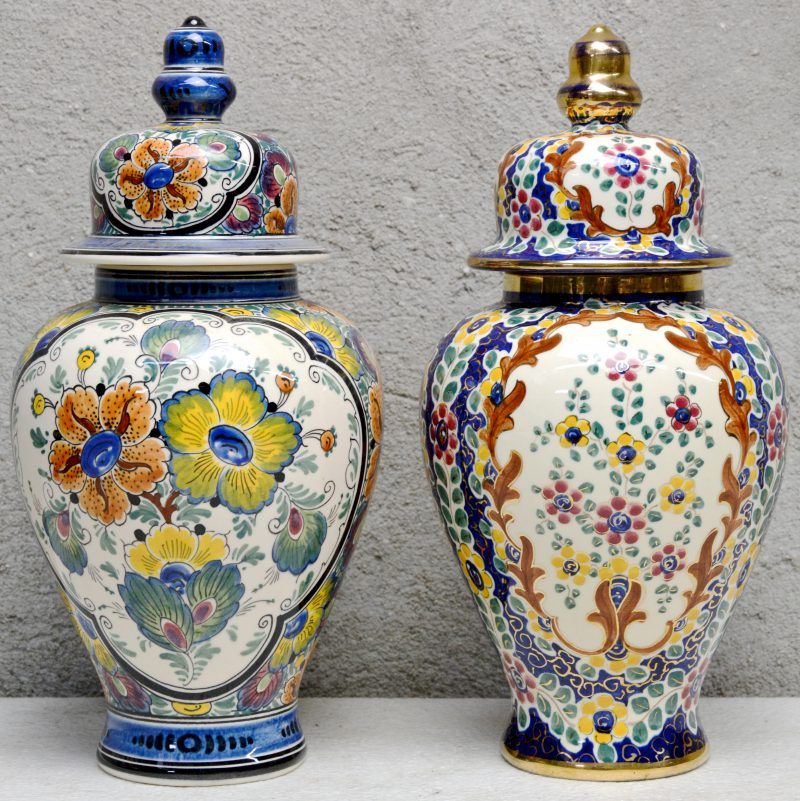Twee dekselvazen van meerkleurig aardewerk, versierd met bloemendecors. Onderaan gemerkt.