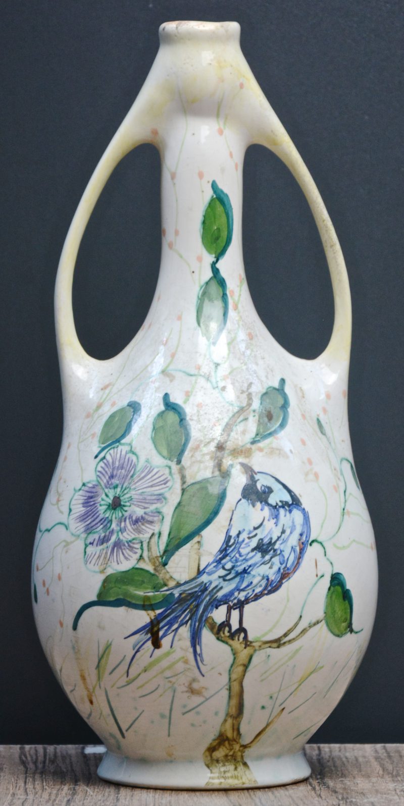Een art nouveau vaas van Gouds aardewerk, versierd met een meerkleurig decor van een vogel en bloemen. Onderaan gemerkt.
