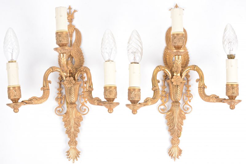 Een paar verguld bronzen wandlampen met telkens drie lichtarmen, waarvan twee in de vorm van zwanenhalzen.