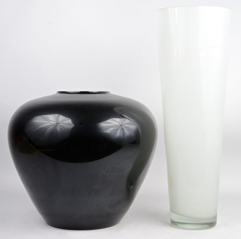 Een lange vaas van wit glas en een lage vaas zwart glas.