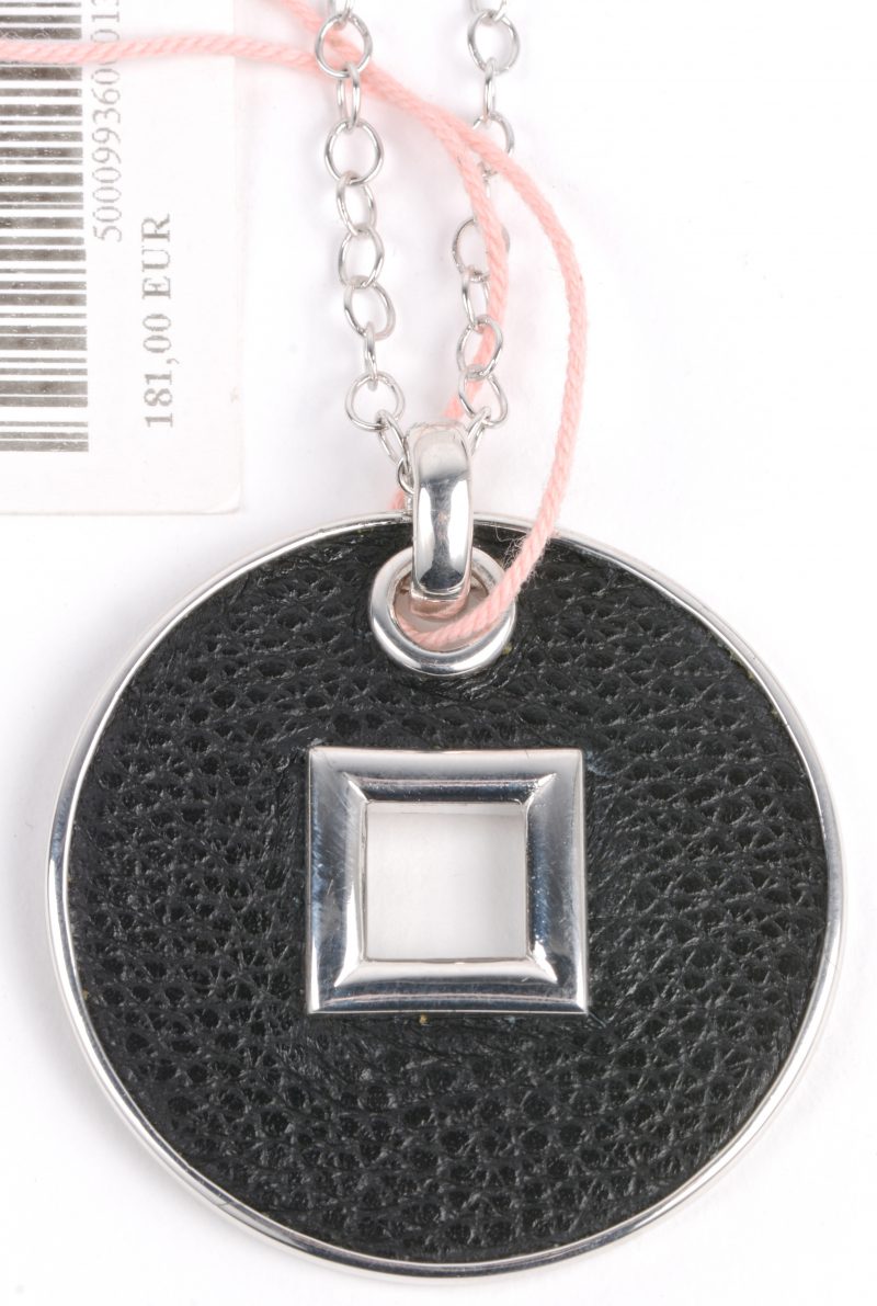 Een zilveren ketting met hanger van zilver en zwart leder. 925‰.